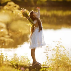 Dziewczynka łapiąca promienie słońca nad brzegiem jeziora