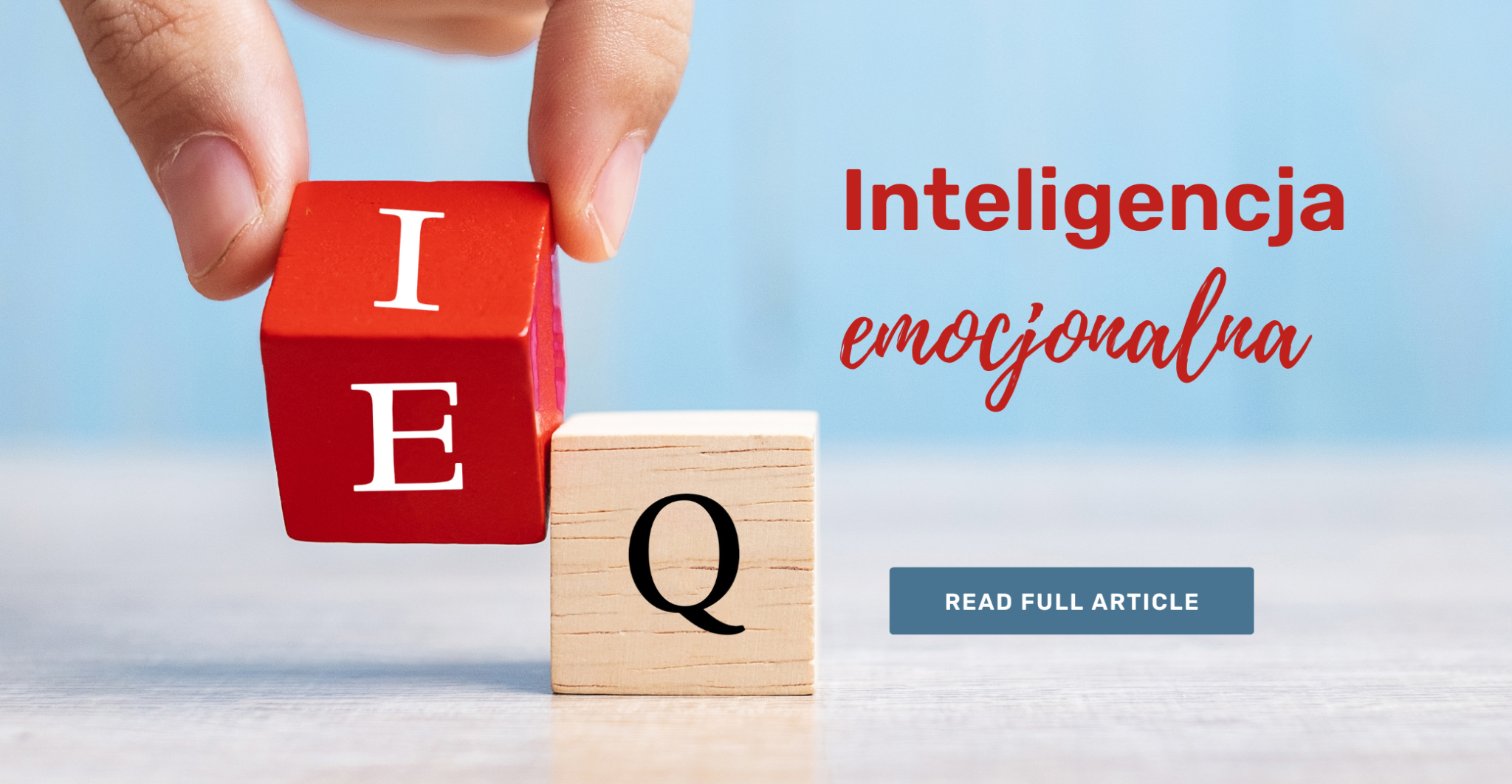 Dłoń układająca drewniane klocki z literami, obok napis „Inteligencja emocjonalna”