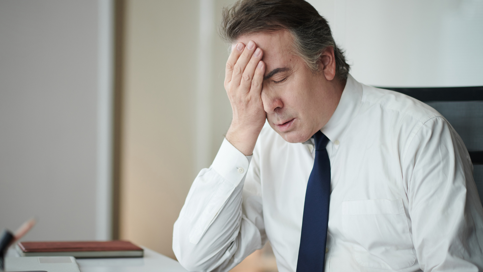 Mężczyzna opierający głowę na dłoni w geście zmęczenia lub zmartwienia