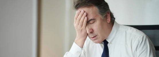 Mężczyzna opierający głowę na dłoni w geście zmęczenia lub zmartwienia