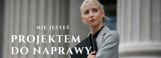 Kobieta w szarym płaszczu z teczką na tle kolumn