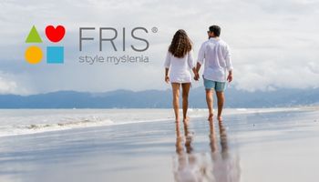 Para ubrana spacerująca brzegiem morza, trzymając się za ręce